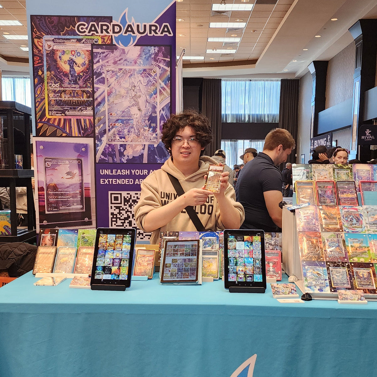 Person at a Card Aura booth with trading card display and promotional materials.
